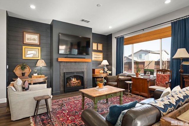 living area featuring a warm lit fireplace, wood finished floors, visible vents, and recessed lighting