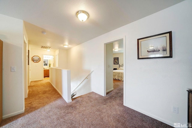 corridor featuring carpet, baseboards, visible vents, and an upstairs landing