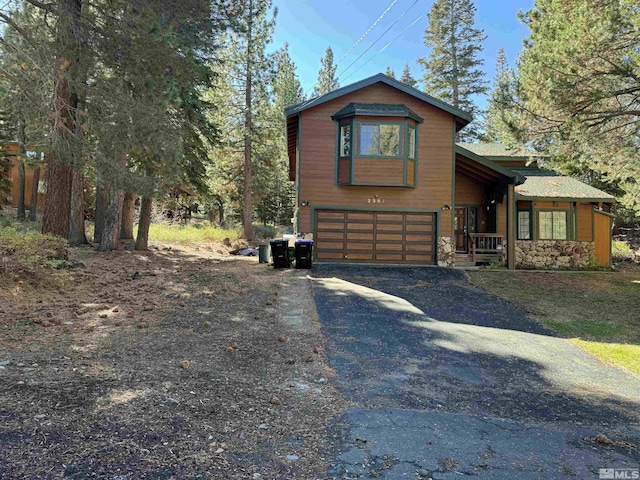 chalet / cabin with stone siding, driveway, and an attached garage