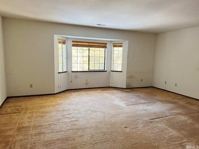 carpeted empty room featuring visible vents and baseboards