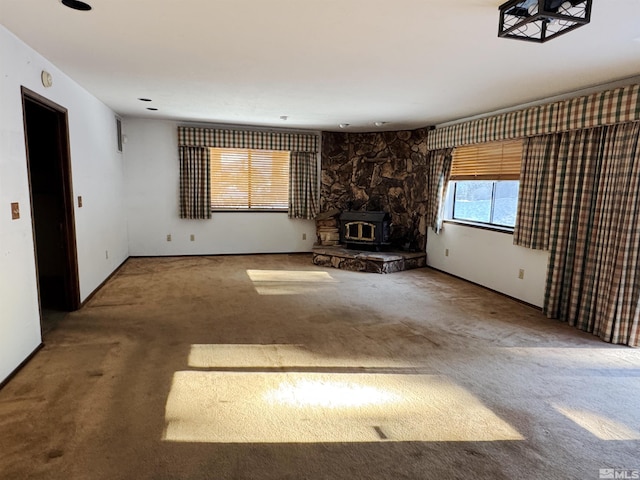 unfurnished living room featuring a wood stove and carpet