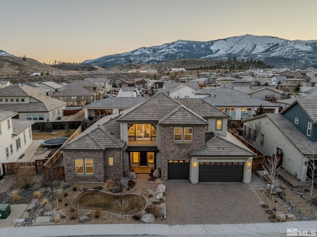 view of front of home with a residential view, fence, a mountain view, and decorative driveway