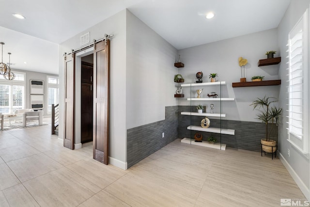 hall featuring recessed lighting, visible vents, baseboards, and a barn door