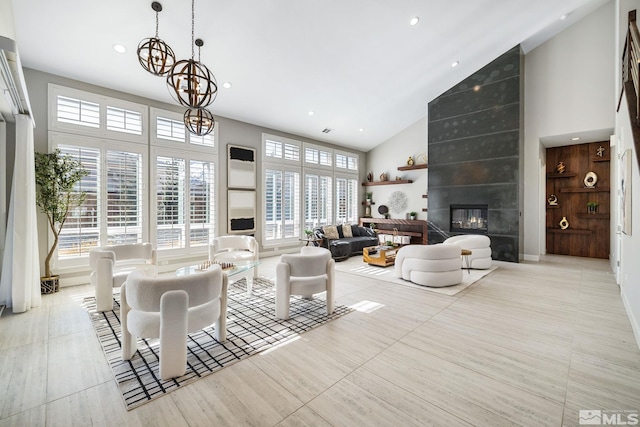 living room with an inviting chandelier, a fireplace, high vaulted ceiling, and recessed lighting