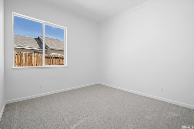 empty room featuring carpet, ornamental molding, and baseboards