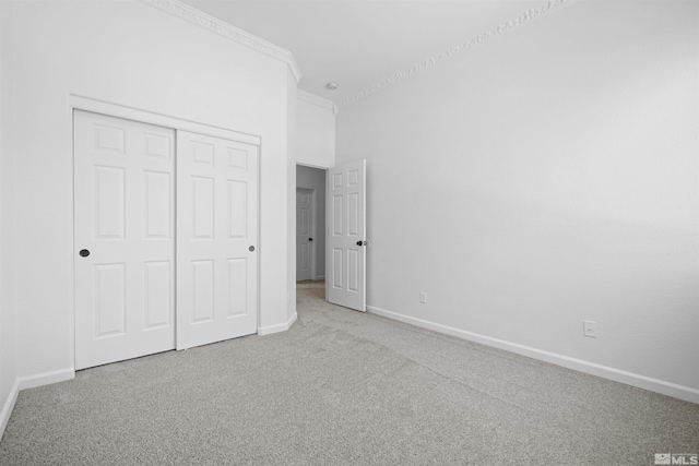 unfurnished bedroom featuring carpet, a closet, crown molding, and baseboards