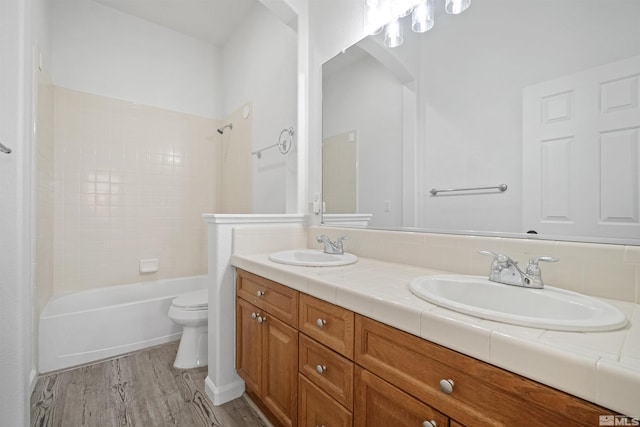 full bath featuring double vanity, wood finished floors, a sink, and toilet