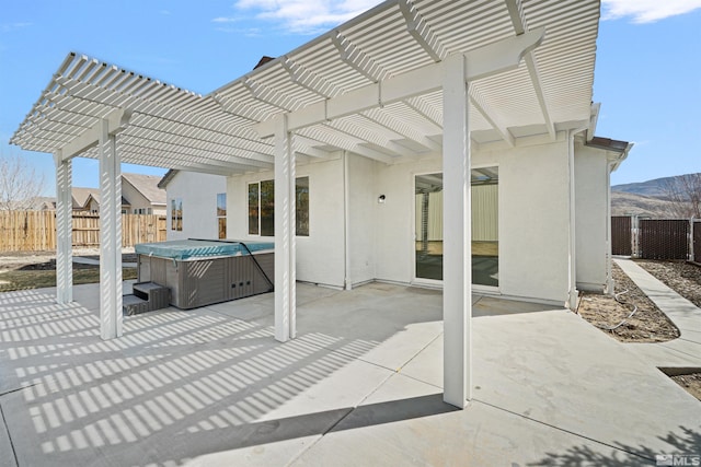 view of patio with a hot tub, fence, and a pergola