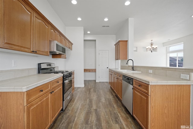 kitchen featuring dark wood finished floors, stainless steel appliances, light countertops, visible vents, and a sink