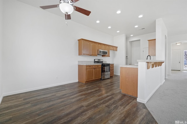 kitchen with arched walkways, recessed lighting, light countertops, stainless steel microwave, and gas stove