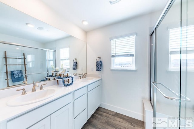 bathroom featuring a healthy amount of sunlight, a sink, a shower stall, and wood finished floors