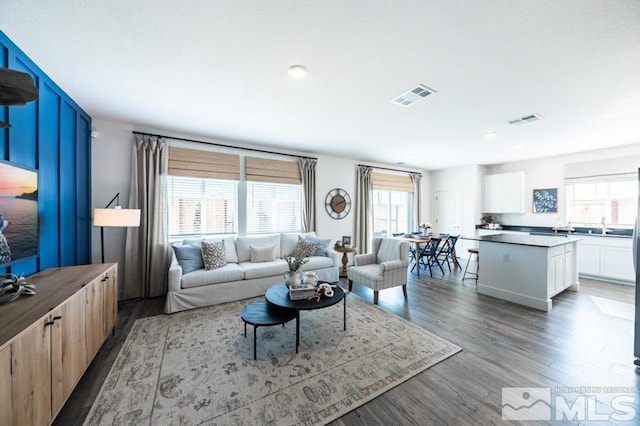 living area with a wealth of natural light, wood finished floors, and visible vents