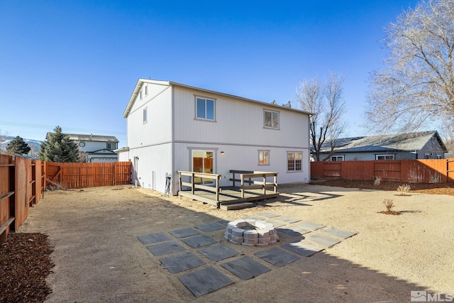 rear view of property with a patio area, a fenced backyard, and a fire pit