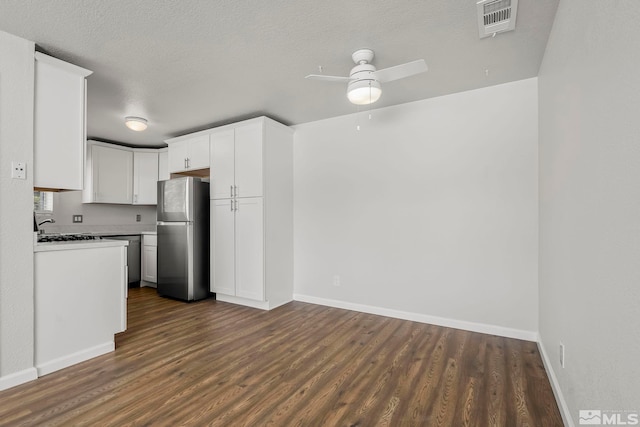 kitchen featuring visible vents, white cabinets, a ceiling fan, dark wood-type flooring, and freestanding refrigerator