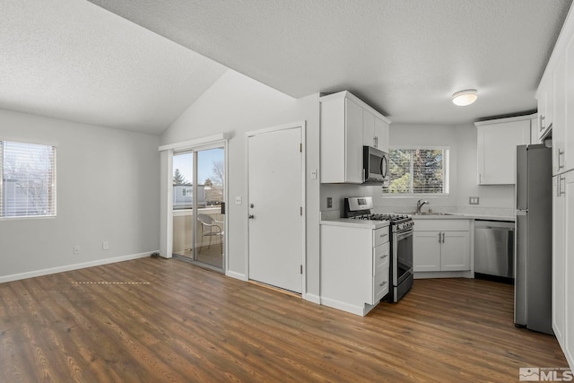 kitchen featuring dark wood-style floors, appliances with stainless steel finishes, light countertops, white cabinetry, and a sink