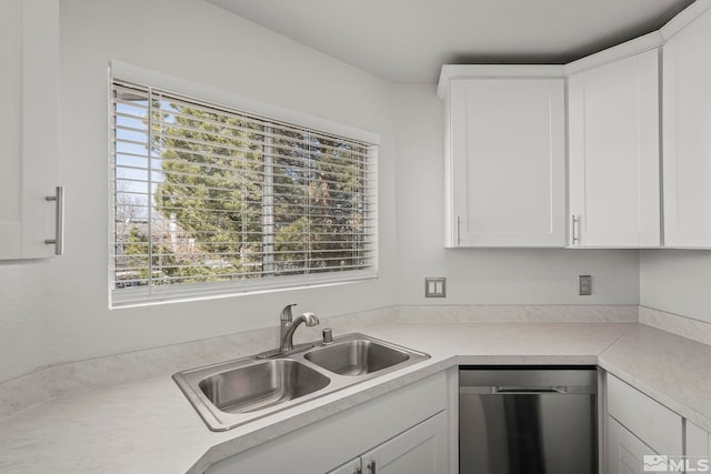 kitchen with white cabinets, light countertops, a sink, and stainless steel dishwasher