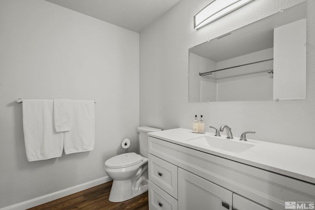 bathroom featuring toilet, vanity, wood finished floors, baseboards, and walk in shower