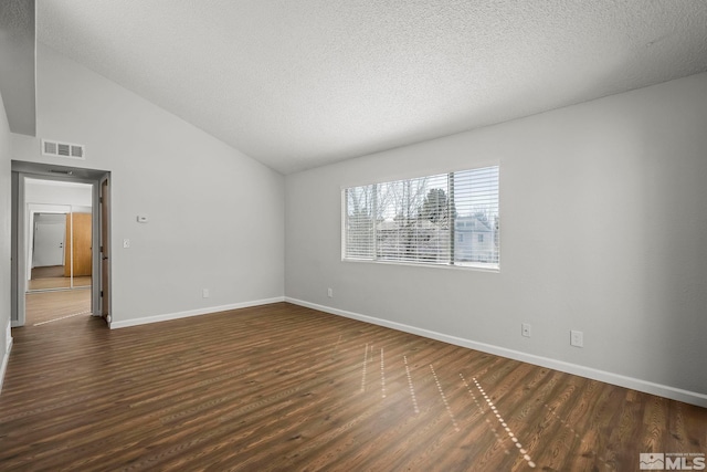 empty room featuring lofted ceiling, a textured ceiling, visible vents, baseboards, and dark wood-style floors