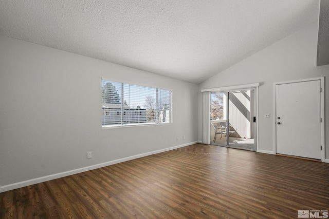 spare room featuring lofted ceiling, dark wood-style flooring, a textured ceiling, and baseboards