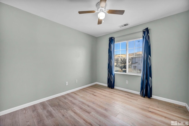 spare room with baseboards, visible vents, ceiling fan, and wood finished floors