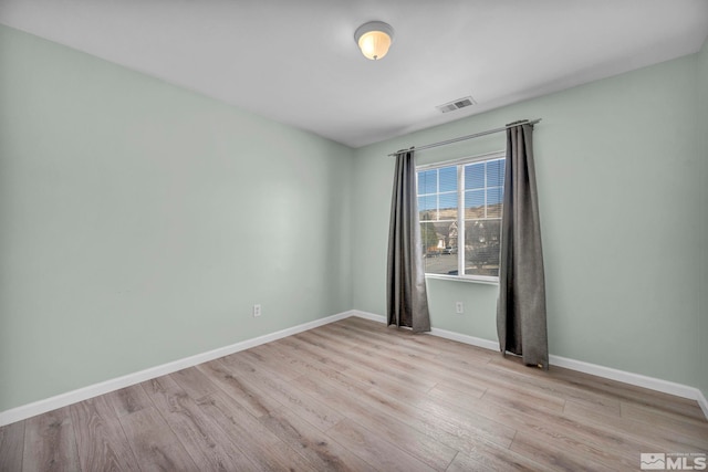 spare room featuring visible vents, baseboards, and wood finished floors