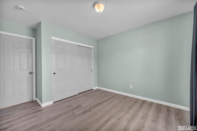 unfurnished bedroom with a closet, baseboards, and wood finished floors