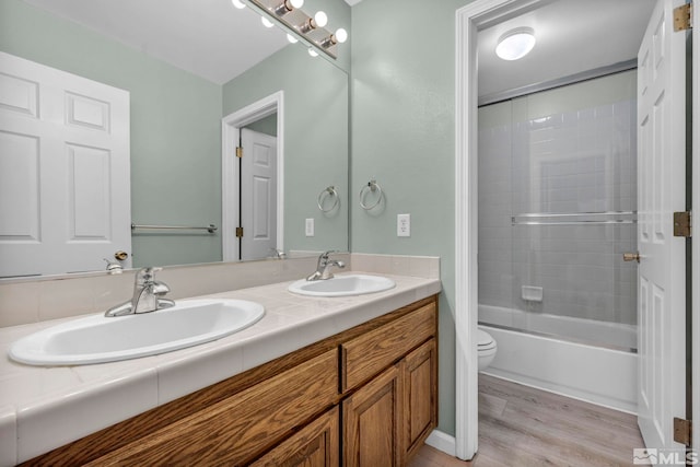 full bathroom featuring toilet, double vanity, a sink, and wood finished floors