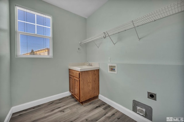 washroom featuring baseboards, electric dryer hookup, light wood-style floors, washer hookup, and a sink