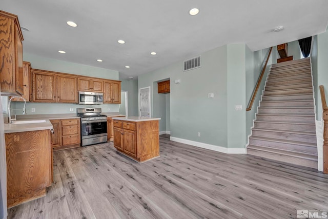 kitchen with a sink, visible vents, light wood-style floors, light countertops, and appliances with stainless steel finishes