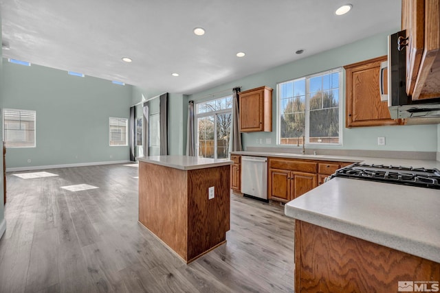 kitchen with open floor plan, appliances with stainless steel finishes, light wood-type flooring, and a center island