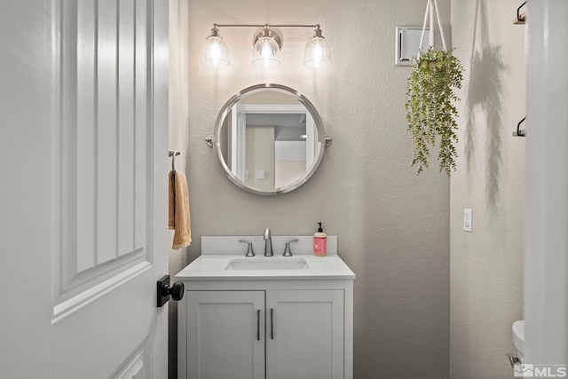 bathroom featuring a textured wall, vanity, and toilet