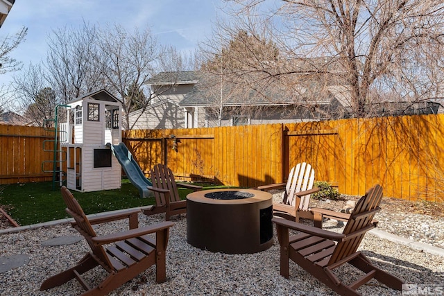 view of patio with an outdoor fire pit, a playground, and a fenced backyard