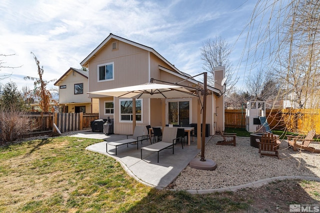 back of house featuring an outdoor fire pit, a fenced backyard, a chimney, and a patio