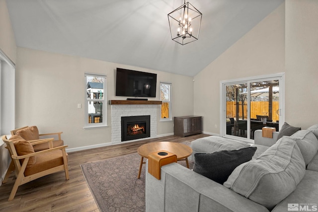 living room with high vaulted ceiling, a fireplace, baseboards, and wood finished floors