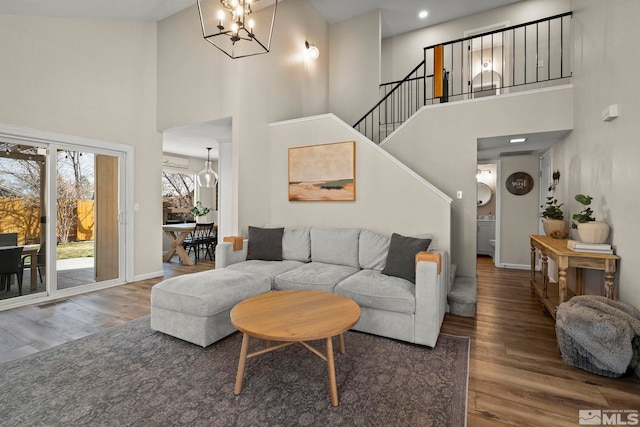 living room featuring a high ceiling, wood finished floors, and an inviting chandelier