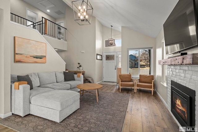 living room with a notable chandelier, a fireplace, baseboards, and hardwood / wood-style flooring