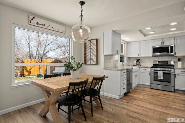 kitchen with appliances with stainless steel finishes, backsplash, plenty of natural light, and wood finished floors