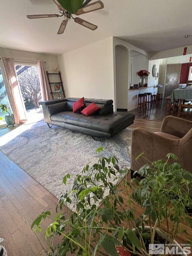 living room with ceiling fan, arched walkways, and wood finished floors