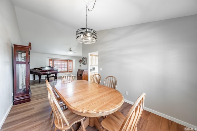 dining room with lofted ceiling, light wood-type flooring, a ceiling fan, and baseboards