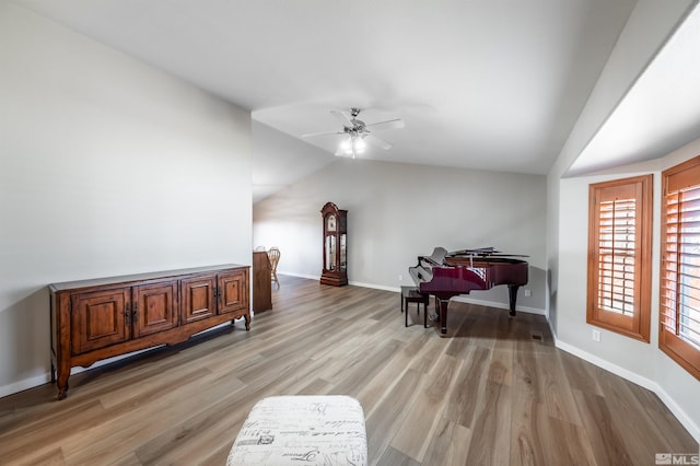 sitting room with lofted ceiling, baseboards, a ceiling fan, and light wood-style floors