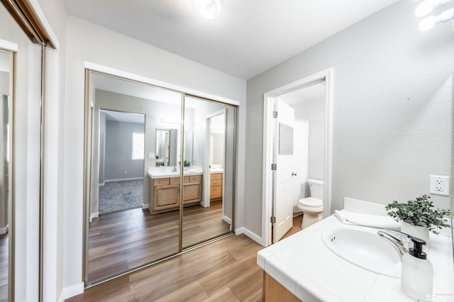 bathroom featuring baseboards, vanity, toilet, and wood finished floors