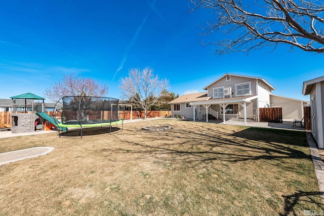 view of yard featuring a patio, a trampoline, a playground, and a fenced backyard