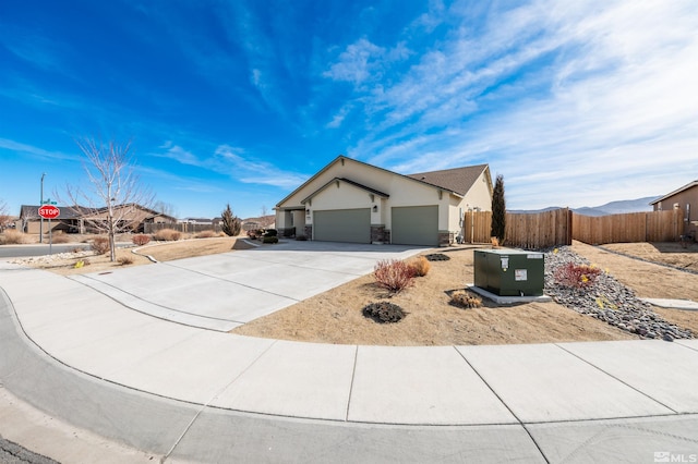 ranch-style home with a garage, concrete driveway, stone siding, fence, and stucco siding