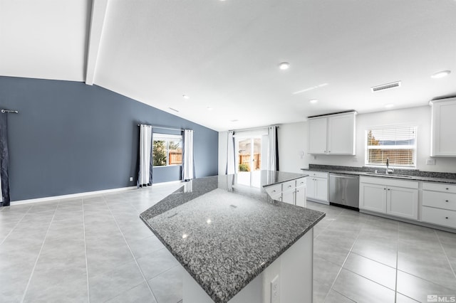 kitchen featuring visible vents, dishwasher, a kitchen island, dark stone countertops, and vaulted ceiling with beams