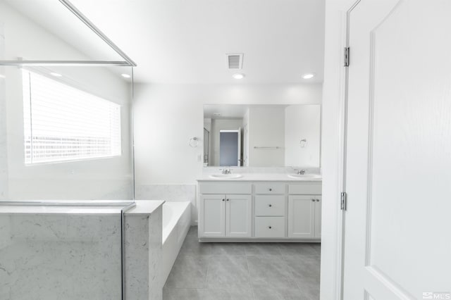 full bathroom featuring double vanity, visible vents, a sink, a bath, and tile patterned floors