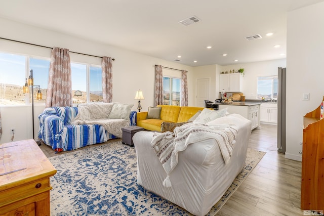 living room featuring recessed lighting, visible vents, light wood-style flooring, and baseboards