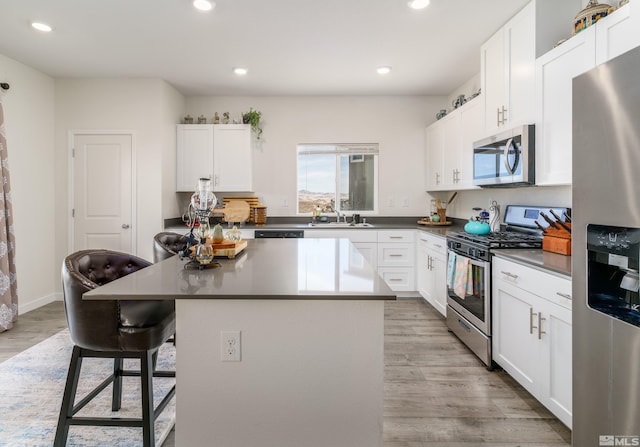 kitchen featuring appliances with stainless steel finishes, a sink, light wood-style flooring, and a kitchen island