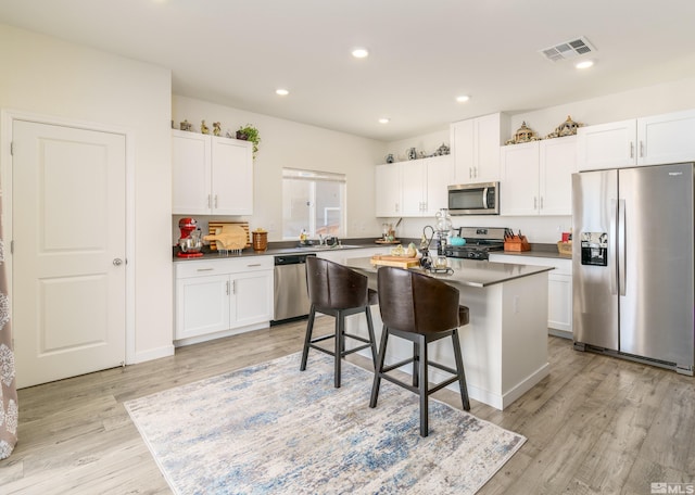 kitchen with visible vents, white cabinets, a kitchen island with sink, stainless steel appliances, and recessed lighting