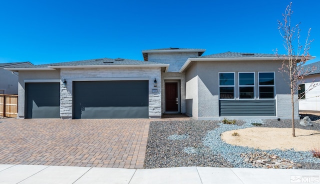 prairie-style home with a garage, decorative driveway, stone siding, and stucco siding