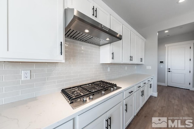 kitchen with decorative backsplash, dark wood finished floors, under cabinet range hood, stainless steel gas stovetop, and white cabinetry